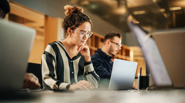 istockphoto-1481370371-612x612 Portrait of Enthusiastic Hispanic Young Woman Working on Computer in a Modern Bright Office. Confident Human Resources Agent Smiling Happily While Collaborating Online with Colleagues.